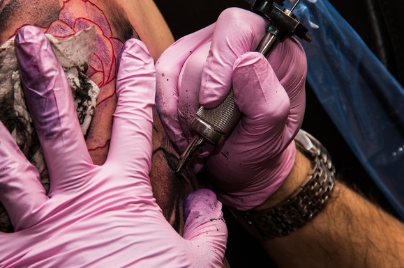 Ein Tätowierer beim Stechen eines Tattoos.