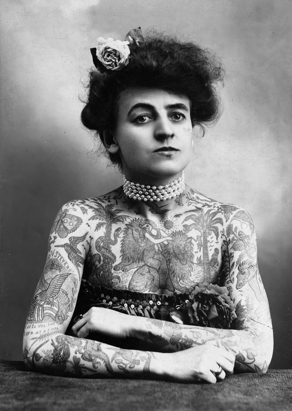 Historische Aufnahme einer Frau mit Tätowierungen auf Oberkörper und Armen